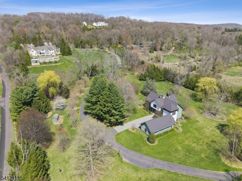 Set behind a gated entrance on 10 private acres, 89-91 Mosle Road is a rare two-residence estate compound totaling approximately 15,000 sqft offering luxury, privacy, and resort-style living. The main residence is approximately 10,000 sqft, with 7BR and 8.2BA. It features a dramatic 2-story foyer with herringbone floors, elegant formal rooms, a cherry-paneled office, and a stunning sunken great room with coffered ceiling and fieldstone fireplace. The newly reimagined 2024 Arclinea chef's kitchen is a showstopper with Wolf/Sub-Zero/Cove appliances, oversized island with dining table, built-in coffee bar, and separate prep kitchen. A private primary wing offers fireplace, multiple walk-in closets, and a spa-like bath with heated floors and Porcelanosa fixtures. The walk-out lower level includes a pub-style bar and billiards room, wine cellar, media/recreation space with projector, and gym. The 3BR, 4.1BA second residence is 5,500 sqft modern farmhouse retreat with 12' ceilings, cathedral living room with barnwood beams, two-story double-sided fieldstone fireplace, and walls of windows overlooking the grounds. Designer kitchen with marble counters and Bertazzoni range, first-floor primary suite, upper-level loft and en-suite bedrooms, plus a full gym and dedicated altitude training room. Resort-caliber grounds include expansive bluestone patios, heated pool with spa, fully equipped pool house, gated drive, lush lawns, and exceptional privacy in the heart of the Somerset Hills.