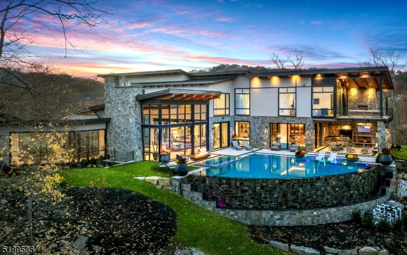 An Aspen, Colorado home on the East Coast? This Modern Day Glasshouse designed by Colorado-based firm, Berglund Architects, sits on an 8-acre private peninsula surrounded by water. Located in the Prestigious Smoke Rise community just 35 minutes from NYC, your serene & peaceful escape awaits. This Private Peninsula Estate features 10,321 square feet of finished living space including 6 bedrooms (2 primary suites), 9 baths, a finished basement lounge, and an 8-car garage with plenty of room for all your off-roading toys. The minute you walk in the front door you will be captivated by floor-to-ceiling windows overlooking a setting that cannot be duplicated. A world-class infiniti pool & spa overlooking Lake Kinnelon, an incredible full outdoor kitchen and fireplace, & a designer tailor-made bar drum-up the most tranquil outdoor backdrop you will ever see. Built in 2022 with a vision in mind for years to come!