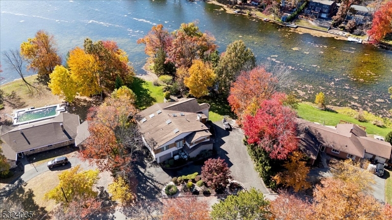 Lakefront Luxury Living on Packanack Lake Experience unparalleled sophistication and luxury in this breathtaking lakefront home with stunning panoramic views. Nestled in the prestigious Packanack Lake community, this one-of-a-kind property includes a private bridge to your own serene island with a tranquil pond & waterfall. This custom home is designed for elevated living & entertaining. Step inside to a grand 2-story foyer that leads to the main level with rich espresso floors, vaulted + beamed ceilings, skylights & walls of windows showcasing lake views in every season. The impressive great room features a floor-to-ceiling stone fireplace & flows seamlessly into the elegant dining area. Sliding doors open to a sunroom, currently a serene office space. The chef's kitchen is a dream, equipped with high-end SS appliances & a spacious quartz waterfall island. The primary suite offers a private sanctuary w/a spa-inspired ensuite, dual shower, freestanding tub & custom WIC. Adjacent to the primary is a large bedroom currently used as a sitting area, providing a private retreat, along with a powder room & laundry room to complete the level. The LL includes 2 bedrooms, one w/an en-suite bath, plus a third full bath, a family room w/a wet bar & a rec-room w/sliding doors to the expansive deck & meticulously landscaped backyard. This is more than a home; it's a lifestyle. Enjoy lake rights & convenience to top schools, dining, parks & more. Unpack & indulge in lakeside luxury!