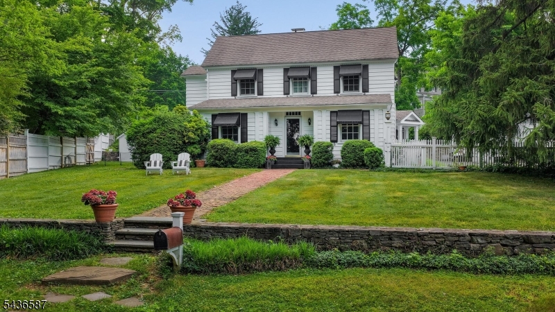 Timeless 1910 charm meets modern convenience in this beautifully updated home, ideally located close to town, schools, and NJ Transit. A welcoming foyer opens to a spacious living room featuring a wood-burning fireplace and a charming library nook with custom built-in bookshelves. The formal dining room is perfect for entertaining and includes French doors leading to a private office or den.The stunning gourmet kitchen is thoughtfully designed with custom cabinetry, quartz countertops and backsplash, a breakfast bar with seating for four, and premium stainless steel appliances. Sliding doors provide easy access to the patio and outdoor living spaces. Open to the kitchen, the impressive vaulted family room showcases a dramatic floor-to-ceiling fieldstone wood-burning fireplace and is complemented by a convenient bar area.Upstairs, the primary suite offers a private en-suite bath, while three additional bedrooms and two full hall baths. The lower level offers flexible unfinished space ideal for a hobby room, workshop, storage, and utilities.Outside, mature stone walls frame the property and create a distinctive setting with access to the upper street. Move right in and enjoy the perfect blend of historic character and today's most desirable amenities.