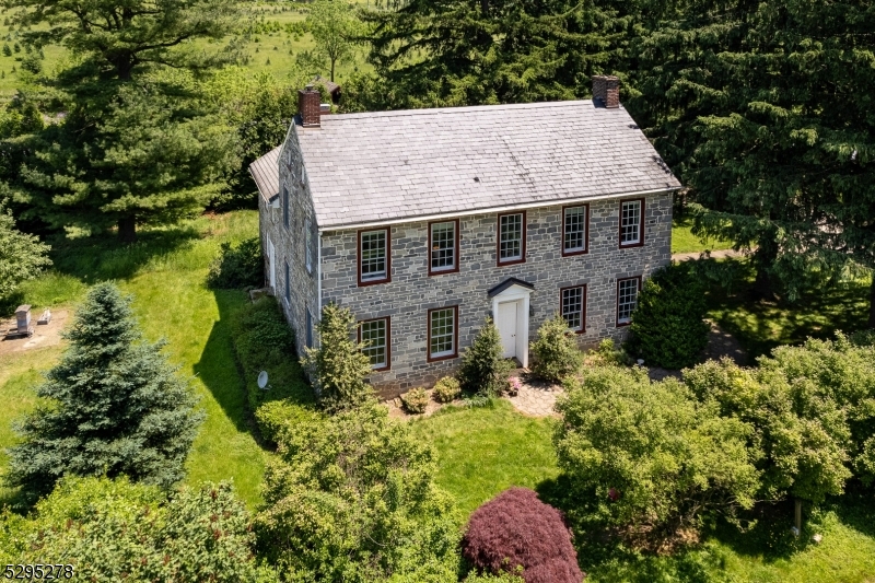 This property offers so much potential in a perfect location along high-visibility Route 22. Among the 38+ scenic acres you'll find a stone farmhouse, multiple outbuildings, and a working Christmas tree farm with a large parking lot. A charming footbridge leads to over 3000 trees of varying species. Two pole barns house machinery and supplies, while a three-bay garage has been partially converted into a gift shop. This center hall colonial dates back to 1790 and includes a kitchen, parlor, dining room, mudroom with hidden laundry, and a full bath on the first floor. High ceilings, deep-sill windows, unique built-in elements, and a transom-topped front door all add to this home's inimitable character. The farmhouse features four non-working fireplaces, and in the original kitchen which is now a parlor, history lovers will appreciate a functioning fireplace with a 12 foot hearth and original ovens. Upstairs, there are two spacious bedrooms and an updated bathroom. The home also has two separate attic spaces that could be finished into additional living space. This property has numerous possibilities given its commercial zoning and ideal location, and it's just waiting for you to make it your own. The land is currently farmland-assessed.