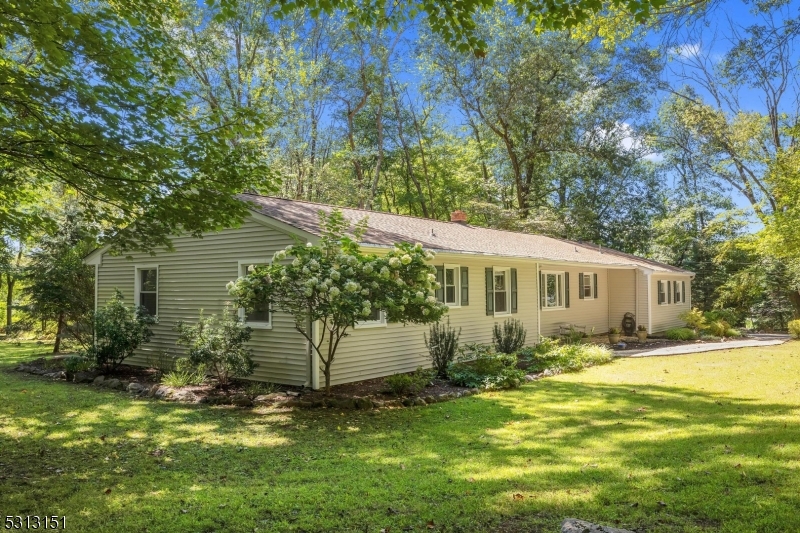 One floor living in park-like setting! Flexible living space with full in-law suite with separate entrance, full bath, kitchenette, bedroom w/walk-in closet, family room and attic storage. Main area of home offers additional 3 bedrooms plus office and 2 full baths. Hardwood flooring, living room with views of the backyard and floor to ceiling brick woodburning fireplace w/Heatolator, formal dining room, large eat-in kitchen. Brand new 4 bedrooms septic to be installed prior to closing. Backyard features barn storage, deck, greenhouse and open and shaded space backs to protected land, so what you see is what you'll always have!  Automatic generator, well pump 10 years old. Long Valley Schools and West Morris Central High School with IB Program. Deck and garage as-is; fireplace as-is, no known defects.