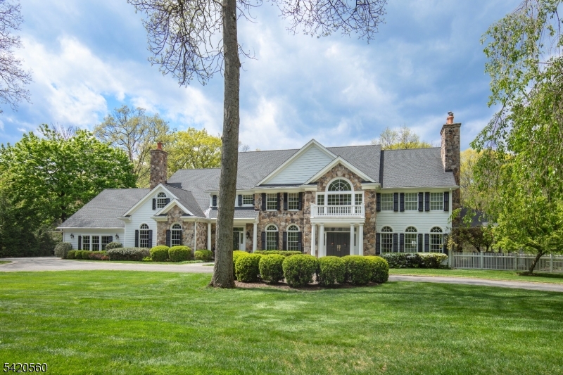 A private lifestyle property set on over two acres in Chester Township, 9 Green Hill Road presents timeless appeal in a beautifully designed Buck's County Colonial. A sweeping drive introduces the custom stone and Hardie Plank exterior, while paver and bluestone hardscaping lead to a soaring foyer flanked by formal living and dining rooms with fireplace and built-in storage. The two-story great room with fireplace and French doors overlooking the backyard serves as the centerpiece for entertaining. The country kitchen features a wall of windows, breakfast island seating, white cabinetry, separate Sub-Zero refrigerator and freezer, six-burner range, dining area, pantry, mudroom, and access to rear patios. The adjacent family room offers high ceilings, wood floors, stone fireplace, and plumbing for a future wet bar. A separate entrance leads to an in-law suite with bedroom, sitting room, full bath, and patio access. A private office with wet bar and doors to the covered bluestone patio overlooking the pool and perennial gardens completes the first floor. The second level features a stunning primary suite with fireplace, dual walk-in closets, and spa bath with jetted tub, glass-enclosed shower, separate vanities, and water closet. Four additional ensuite bedrooms, including one with private balcony, and a laundry room complete the level. A three-car garage with high ceilings offers space for auto lifts, while a full unfinished walkout lower level brings evermore opportunities.