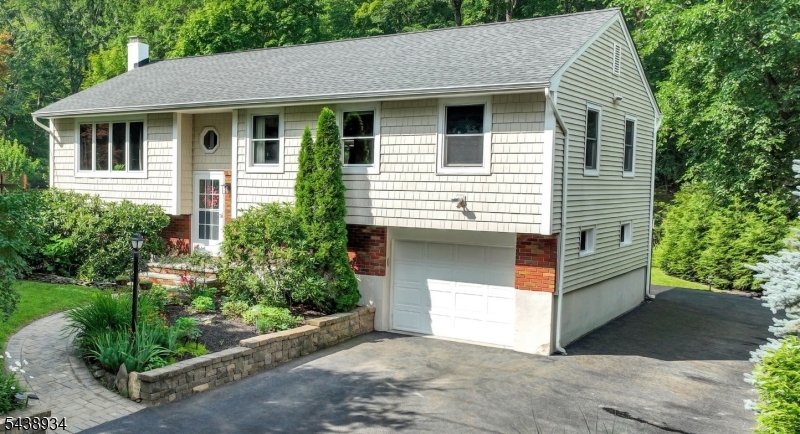 A backyard sanctuary like no other in lower West Milford with quick and convenient access! Updated home nestled in nature, surrounded by mature lush trees, natural hardscape, garden bridge over tranquil stream in distant rear of yard. Garden deck. Natural gas. Wood floors. Newer: roof w/ice guards, central air, hot water baseboard heating, Pella windows, well pump and holding tank, 200 amp electrical service. Kitchen with quartz counter, breakfast bar, stainless steel appliances. Living room with bay window open to dining room with French doors to 3 season room overlooking beautiful backyard with access to deck. Great lower level with extended living space, complete with summer kitchen, bedroom/office, full bath and family room with direct access to covered patio, hot tub and fire pit. Shed, dog fence, alarm system, generator hook-up. Minutes to shopping, restaurants, schools and town center.