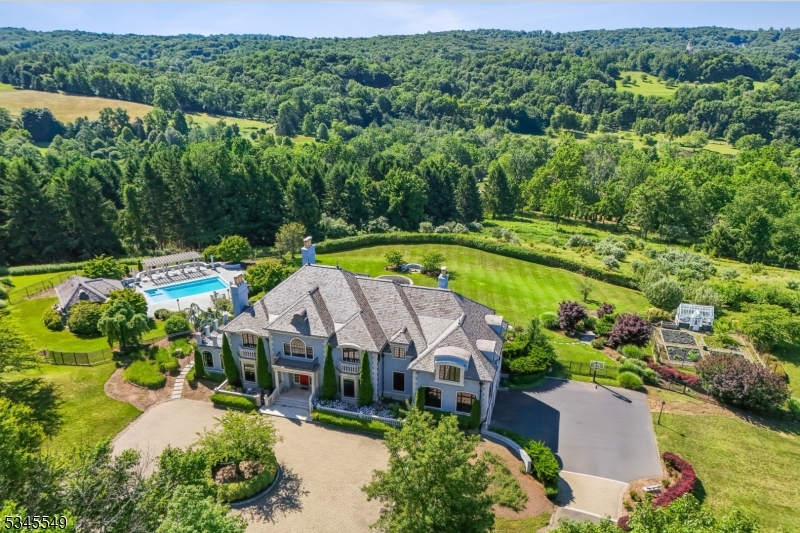 Originally modeled after the grandeur of the Palace of Versailles and nestled in a serene setting with breathtaking views from every angle, this exquisite 6-bedroom estate was completely transformed in 2020 to a modern architectural masterpiece. A private gated drive winds up to this extraordinary residence, with impeccable attention to detail in every corner. Designed to impress, this home offers a perfect blend of opulence & comfort, ideal for both grand-scale entertaining & intimate gatherings. Step outside into the stunning manicured gardens, where lush greenery & vibrant blooms surround you. Adding to the charm is an authentic English greenhouse, with its own dedicated water supply, ideal for nurturing your favorite plants year-round. The estate also boasts a sprawling apple orchard, offering seasonal fruit & a peaceful countryside atmosphere. The remodeled pool area provides the perfect oasis. A fully equipped pool house features a full bath & kitchen, making it ideal for both hosting poolside gatherings or enjoying a day of relaxation. Inside, state-of-the-art systems further elevate the home's appeal, including a Savant home automation system, sophisticated video security system & a high-end home theater. A built-in generator ensures that these luxuries continue uninterrupted. This remarkable estate offers an exquisite lifestyle for those at the pinacle of success, where every turn presents beauty, luxury and an escape from the ordinary.