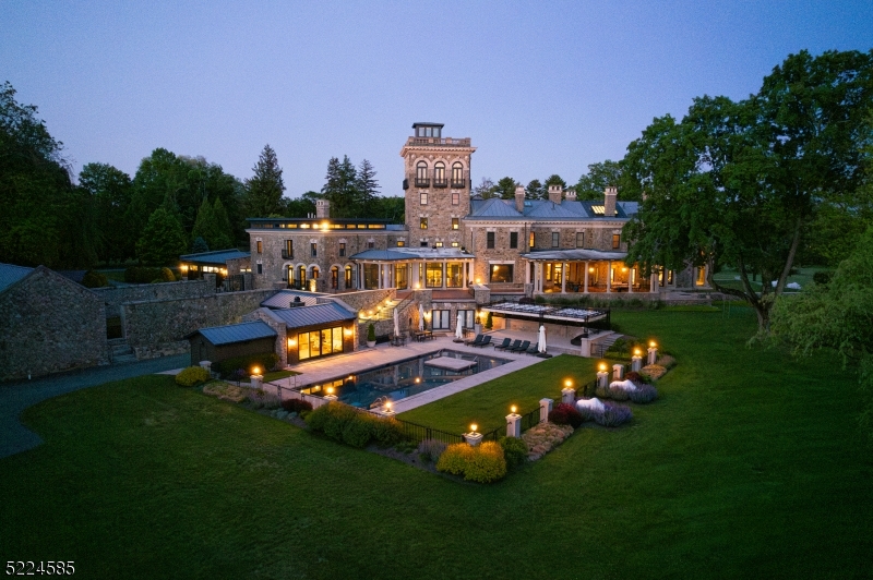 Rarely does a property come to market that melds the rich heritage of 19th century Somerset Hills and the ultimate in modern form and function of the 21st century. The home has been brilliantly reimagined to meet today's updated wants and needs. Set amid 32 lush acres, this majestic residence is an architectural masterpiece. The original interior appointments of the home have all been painstakingly restored with the greatest of care. The whimsical and eclectic interior design is the perfect counterpoint to the home's classical architecture. The thoroughly modernized and expanded kitchen adjoins a breakfast room and comfortable two-story family room and provides the ideal setting for day to day life. A wall of glass doors brings the outdoors in and leads to a terracotta terrace with outdoor kitchen and stairs that lead to the pool, pool house and grounds. A most unique feature of the home is the tower offering a sophisticated lounge/bar as well as a breathtaking office and rooftop deck with views as far as the eye can see. The home has a Savant Smart Home System and can be remotely controlled via smartphone. The swimming pool with limestone deck, covered cabana and pool house with kitchenette and wood burning fireplace, overlook this stunning property. There is also a full property generator and elevator to 6 levels of living, a carriage house with 3 beds, 2.1 baths and 5 car garage and a gymnasium with full-sized basketball court, workout room, kitchenette and change rooms.