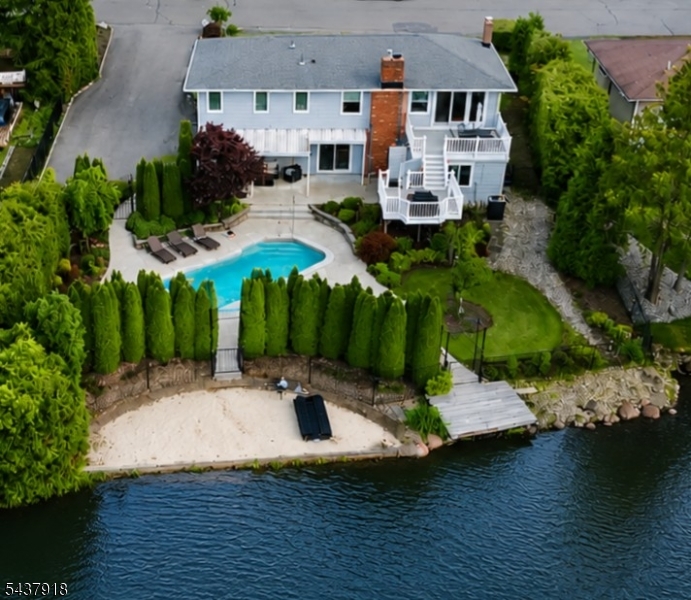 Situated in the sought-after, premier section of West Milford known for its natural beauty and exceptional lifestyle, this stunning property offers the perfect blend of privacy, recreation, and everyday comfort. Experience exceptional lakefront living in this beautifully maintained 3+ bedroom, 2.5-bath home offering breathtaking water views and resort-style amenities. Situated on a prime waterfront lot, this property features a private sandy beach and dock, as well as a heated in-ground saltwater pool, creating the perfect setting for boating, swimming, fishing, and entertaining. Inside, you'll find comfortable living areas designed for relaxation. Two fireplaces provide warmth and ambiance, while large windows showcase the stunning lake views and fill the home with natural light. Step outside to enjoy your own private oasis, complete with beautifully landscaped grounds, expansive patio areas, and multiple spaces to relax or entertain while taking in the tranquil waterfront setting. Whether you're enjoying a morning coffee overlooking the lake, hosting poolside gatherings, or watching spectacular sunsets from your private beach, every day feels like a vacation. Additional features include a whole-house Generac generator for peace of mind. Beyond the property, enjoy a vibrant, friendly community with activities and events throughout all seasons, offering year-round opportunities for recreation and social gatherings. Don't miss this rare waterfront opportunity.