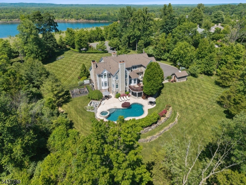 Nestled on over two professionally landscaped acres in one of Basking Ridge's most prestigious neighborhoods, this exceptional colonial situated on a quiet cul-de-sac & showcases breathtaking mountain, skyline, sunrise, sunset views. Meticulously maintained & thoughtfully updated, this elegant home offers 6 bedrooms, 6 full baths, half bath, blending timeless architecture with resort-style living. The custom cherry kitchen features professional-grade appliances, premium Waterstone fixtures, a large center island, octagonal breakfast room with tray ceiling & walls of windows framing spectacular views. Sliding doors open to an expansive deck overlooking the private backyard. The kitchen flows into the spacious family room, creating an ideal setting for entertaining. Architectural details include coffered ceilings, extensive custom millwork, 3 fireplaces. A richly appointed mahogany-paneled office with custom built-ins. The luxurious primary suite features a fireplace, spa-inspired bath with premium Symmons shower system, 2 oversized walk-in closets. The fully renovated walkout basement in 2021 offers recreation & fitness area, a full bath, temperature-controlled wine cellar. Resort-style yard include a heated saltwater pool, rose gardens, mature fruit trees. Major updates include custom closet (2021),  driveway (2024), new roof, pool deck,insulated garage door (2025). Just minutes from top-rated schools, shopping, this remarkable estate offers luxury living at its finest.