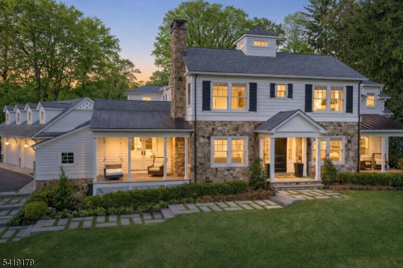A seamless blend of refined design and thoughtful layout defines this beautifully crafted home, offering an ideal balance of elegant entertaining spaces and effortless everyday living. The main level features a spacious eat-in kitchen that flows into the family room and extends directly to the expansive patio, creating a seamless indoor-outdoor connection ideal for both daily living and entertaining. A formal dining room, living room and private den provide distinct yet cohesive spaces for gathering or quiet retreat, while a first-floor bedroom offers flexibility for guests or office use. A well-appointed mudroom and laundry area connects directly to the garage, adding functionality and everyday ease. Upstairs, the primary suite serves as a private sanctuary with generous proportions, generous walk-in closet and spa-inspired bath designed for relaxation. Additional bedrooms are well-sized and thoughtfully positioned, including one with charming architectural lines, built-in window seat and dedicated workspace. A central study area and second-floor laundry enhance comfort and convenience. The finished lower level offers a spacious recreation area ideal for entertaining or relaxing, along with additional storage options. Outdoors, the patio is anchored by a fire feature and multiple seating areas, creating the perfect setting for gatherings. The expansive lawn beyond offers room for recreation, framed by mature trees that provide both privacy and a serene natural backdrop.