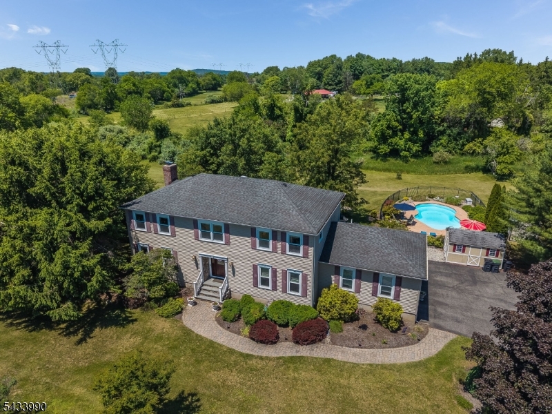 Welcome to this beautifully maintained 4-bedroom, 2 full and 1 half bath colonial set on a picturesque property in desirable Readington Township. Thoughtfully updated and meticulously cared for, this home offers the perfect blend of comfort, functionality, and outdoor living. The main level features hardwood flooring throughout, a cozy living room, formal dining room with custom woodwork, and a spacious family room highlighted by custom built-ins and a wood-burning fireplace. The updated kitchen is designed for both everyday living and entertaining, featuring granite countertops, stainless steel appliances, center island seating, abundant cabinetry, and direct access to the expansive covered deck overlooking the backyard. A convenient first-floor laundry room and powder room complete the main level. Upstairs, the primary suite offers a walk-in closet and beautifully renovated bath with a custom double vanity and oversized tiled shower. Three additional bedrooms and a second full bath provide ample living space. The finished basement adds exceptional flexibility with recreation space, an exercise room, utility room. Step outside to enjoy the resort-like setting featuring a large deck, patio, beautifully landscaped grounds, and an in-ground pool creating the perfect space for relaxation and entertaining. Conveniently located near shopping, dining, parks, and major commuting routes, this exceptional home offers the lifestyle you've been waiting for.