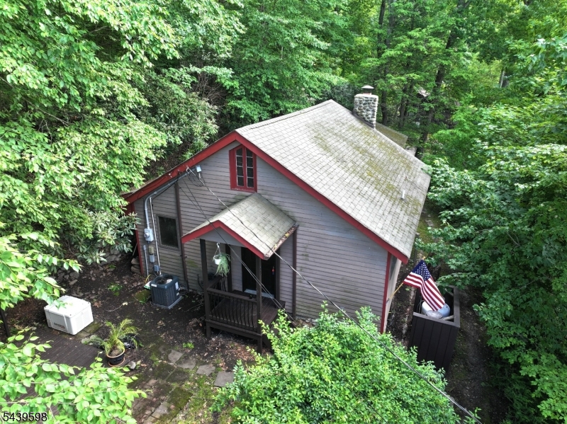 Charming lake-style retreat offering 2 bedrooms and 1 full bath, with hardwood flooring throughout and seasonal views of Kittatinny Lake. Relax and entertain on the outdoor patio while enjoying the peaceful lake community setting. The inviting living room features a stunning stone fireplace, vaulted beamed ceilings, and seasonal lake views that bring natural beauty indoors. A spacious country kitchen offers ample counter space for cooking and gathering, while an additional dining or sitting room provides flexible living space to suit your needs. The tiled full bath includes a tub/shower combination. A large utility/laundry room offers convenient access to the backyard and features a staircase leading to a walk-up attic, presenting exciting possibilities for future expansion, storage, or creative use. Additional highlights include central air conditioning and a whole-house generator for year-round comfort and peace of mind. Enjoy all that Kittatinny Lake has to offer, including non-motorized boating, a community clubhouse, beach, multi-use sports court, and playground. Whether you're seeking a year-round residence or a weekend getaway, this home offers the perfect blend of comfort, character, and lake community living.