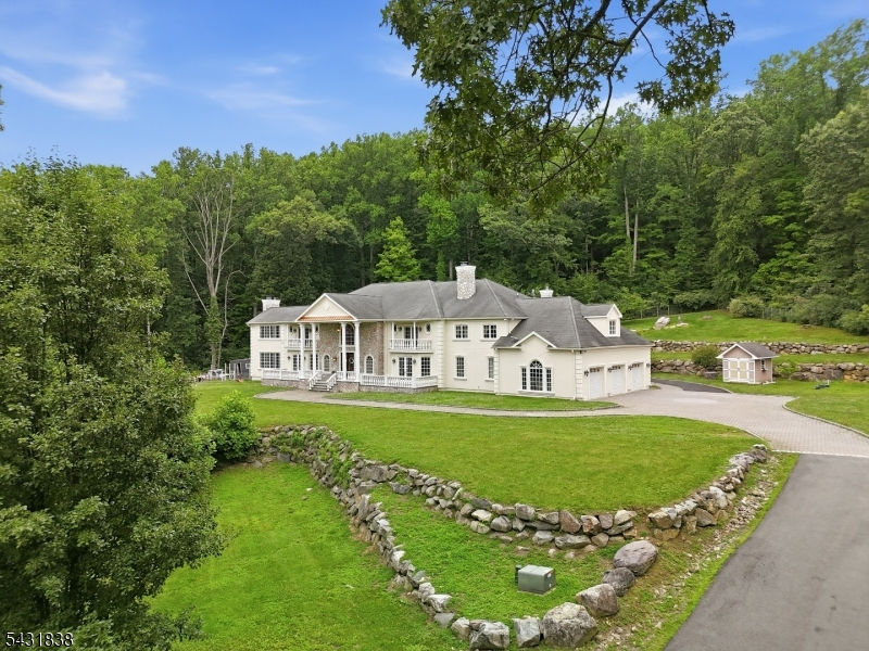 Extraordinary custom-built estate situated on 12 private acres. Main residence features approximately 9,067 square feet of living space with an additional 4,000+ SF in the full walk-out basement. An elegant stone front porch leads to a grand two-story foyer showcasing marble floors, custom moldings, coffered ceilings, and a dramatic Cinderella staircase. Stunning architectural details found throughout home, including HWF, custom millwork, and beautifully designed living spaces. 5 bedrooms, 5 full and 2 half bathrooms, including 2 luxurious primary suites, featuring a private sitting room, gas fireplace, walk in closet, and full bath. Main-level office with dual fireplace open to Dining Room. Formal great room with wood burning fireplace and custom bar. The gourmet kitchen is equipped with custom cabinetry, stainless steel appliances, granite countertops, and a large walk-in pantry. Amenities include a whole-house speaker system, central vacuum, Andersen and JELD-WEN windows, dual 200-amp service panels, whole-house generator, main-floor laundry room, and a 3-car garage. Outside, enjoy resort-style living with a stunning two-level patio featuring accent lighting, an outdoor pizza oven, fire pit, and an above-ground pool w deck surround. Freestanding bungalows, each offering BR, LR, kitchen, DR, laundry, and basement being renovated down to the studs with new siding, roofing, windows, and doors, providing outstanding rental income or guest accommodations.