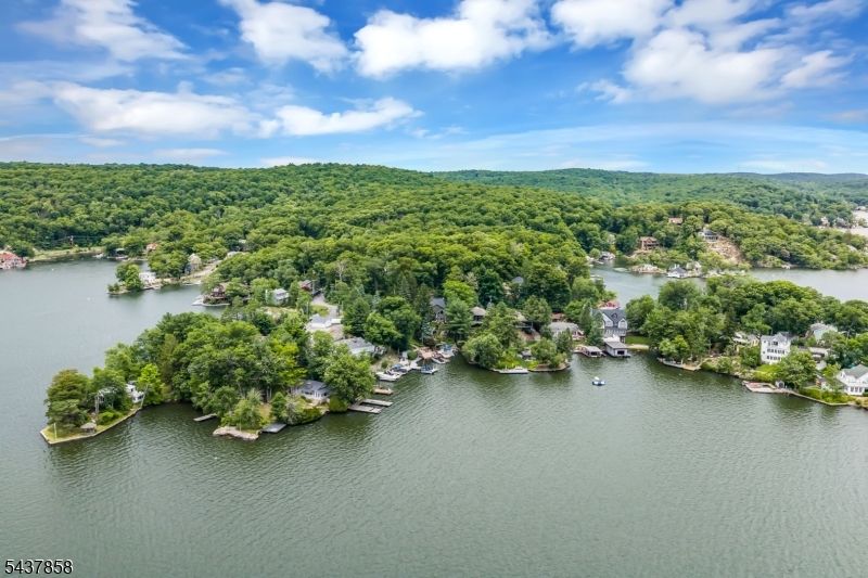 Coveted Cove. Lakefront Luxury Home Fully Rebuilt 2026! More than a renovation, this is a complete reinvention. Rebuilt in 2026 to a standard rarely seen at this price point. Nestled in a private south-facing cove between Pine Tree and Cow Tongue Points with water views across lush, landscaped gardens from every room, this lakefront home captures the best of year-round Lake Hopatcong living. Panoramic floor-to-ceiling south-facing windows frame the lake like a painting. The gourmet kitchen features Taj Mahal island and countertops, Sub-Zero refrigerator wall with wine storage and beverage drawers, Wolf range and wall ovens, custom cabinetry, and fitted bar. Elegant walnut and soft white palette set the tone. Rebuilt bathrooms with frameless glass, stone countertops, custom vanities, Brizo faucets. Bespoke oak and cable-rail staircase. Inbuilt electric fireplaces in living room and loft. Two home offices. Custom fitted closets and oak hardwood floors throughout. All new: high-efficiency boiler, central AC, full electrical rewire, whole-home generator. Outside: stone walls, repainted dock, and multiple entertaining zones to the water. Mornings start in the loft with sun streaming through architectural windows. Kayak from your dock before the lake wakes up. Boat to lunch at one of the lake's 9 restaurants. Return to the terrace for cocktails before dinner around the island. Cozy fire pit on the dock. This is lakefront living at its best private, polished, and move-in ready!