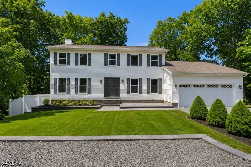 Welcome to this beautifully maintained, sun-drenched colonial home, where classic comfort perfectly balances with modern living. Located in Awosting, one of West Milford's most sought-after neighborhoods, residents enjoy exclusive access to an array of community amenities including a private beach, a local clubhouse, and direct access to Greenwood Lake. From the moment you step through the front door into the bright foyer, you are greeted by an abundance of natural light streaming through large, elegant windows that effortlessly illuminate the spacious, open layout. The main level showcases an expansive living area with pristine hardwood flooring and crisp neutral walls, alongside a beautiful eat-in kitchen complete with warm wood cabinetry, a central island, and sliding glass doors that lead directly outside. Transition seamlessly to the massive rear deck, providing an incredible elevated space for outdoor dining, entertaining, or simply overlooking the serene, green surroundings and meticulously manicured lawn. Downstairs, a full walkout basement offers endless potential for recreation, a home gym, or additional living space with direct backyard access. Complete with a spacious two-car attached garage and exceptional curb appeal that shines both day and night, every corner of this property blends functional architectural charm with bright, airy spaces designed for modern lifestyles.