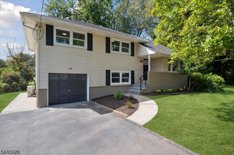 Beautiful & COMPLETELY RENOVATED Split Level Home just waiting for you to move in and enjoy! With 4 bedrooms + 2 1/2 bathrooms and designer details throughout, all set on a corner lot with convenient access to schools, shopping, dining, parks and major highways. Just minutes from 3 Direct Train Stations to New York City . Past an inviting front porch and foyer, the main level opens with gleaming hardwood floors and recessed lighting in the spacious living and dining rooms. Just beyond the beautiful kitchen with classic white cabinets, SS appliances, gorgeous quartz counters, subway tile backsplash and peninsula with extra seating. Wood floors continue upstairs to 3 bedrooms, all serviced by a full hall bath with storage vanity and a tub/shower combo with marble tile and oil-rubbed bronze fixtures. A huge, tranquil primary suite on the top-level features plush carpet, recessed lighting, skylight, 3 closets, sitting area, and an adjoining beautiful en-suite bath with shower. The ground level offers a family room with access to the attached 1-car garage and a big laundry room with outside entry and adjoining half bath, while a pristine basement level houses the utilities. A new paver patio accessible from the dining room & lower level leads out to a sprawling backyard surrounded by mature plantings for privacy, providing ample space for cookouts, relaxing & entertaining. Brand NEW Roof, Doors, Furnace, AC, Water Heater & more. Nothing to do here but unpack!