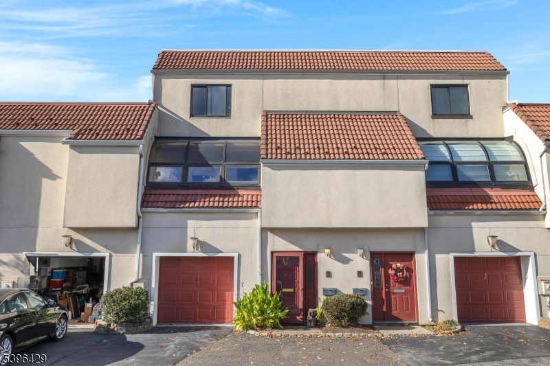 Welcome to Eagle Ridge, a sought-after gated community offering 24-hour security and resort-style amenities. This spacious multi-level townhouse features 2 bedrooms, 2.5 baths, and a 1-car garage. Freshly painted and filled with natural light, the home showcases distinctive Mid-Century-inspired design with clean contemporary lines, built-ins, large windows, and parquet wood floors throughout. The bright galley kitchen stands out with bold red cabinetry, stainless-steel appliances, and sleek finishes, opening to a sun-filled dining area. Both bedrooms are generously sized with ample closet space and access to full baths; the primary suite includes a fireplace and walk-in closet. While move-in ready, the home offers opportunity for personal updates or remodeling to suit your style. Enjoy indoor/outdoor pools, tennis, fitness center, clubhouse, and proximity to shopping, dining, and NYC transportation.