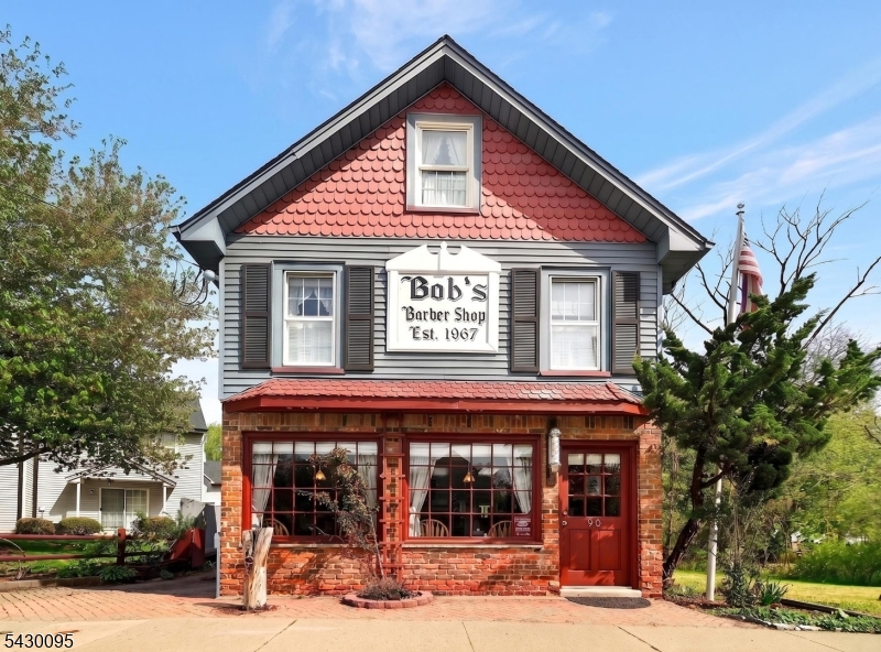 90 Hamburg Turnpike in Bloomingdale, New Jersey offers a rare mixed-use opportunity with residential living and rental income potential. Home to the iconic Bob's Barbershop for generations, this highly recognizable property combines a three-bedroom Colonial with an established commercial space in a prime in-town location.The residential portion features a warm and inviting Colonial with three bedrooms, two full bathrooms, and one half bath. One of the second-floor bedrooms includes a walk-in closet and private full bath, creating a comfortable primary suite setup. The home offers flexible living space with classic charm throughout, two laundry areas for added convenience, and a deck overlooking the property.Outside, you'll find a gravel driveway for parking, a barn-style garage with walk-up attic storage, and a carport. The property also includes an inground pool with a liner replaced approximately three years ago. The pool has not been opened in several seasons and is being conveyed strictly as-is.The commercial portion is occupied by the well-known Bob's Barbershop, one of Bloomingdale's most established neighborhood businesses. The barber shop currently has a five-year lease in place with an option to renew for an additional five years, creating excellent income potential. Live in the home while collecting rental income from this long-established local business. A rare opportunity to own a landmark property with outstanding visibility in the heart of Bloomingdale.