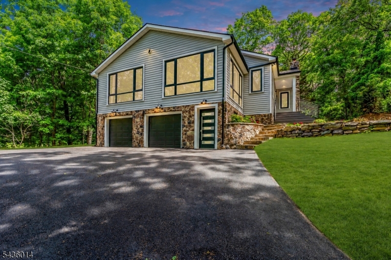 Welcome to a newly built designer home on a private, wooded 0.77-acre lot in Boonton Township. Rebuilt from the studs out in 2026, this 3-bedroom, 2-bath home with 4-season room leaves nothing to do but move in. The chef's kitchen features custom gray shaker cabinets with brass hardware, Calacatta-look porcelain tile, waterfall island, Samsung stainless appliances, quartz countertops, and large-format porcelain floors. The open living area is anchored by a soaring original fieldstone fireplace with live-edge mantel. A 4-season room adds year-round flex space, and the lower level features a second linear electric fireplace with walnut slat accent wall.Both baths are fully reimagined with designer porcelain tile, frameless glass, LED mirrors, and luxury fixtures throughout.Wide-plank white oak hardwood floors, Samsung stacked W/D included, attached 2-car garage with epoxy floor and EV charger, new windows, and professional landscaping with stone retaining walls complete the package. Top-rated Rockaway Valley School. Minutes to Rt. 287 and Morris County rail. This one is the real deal.