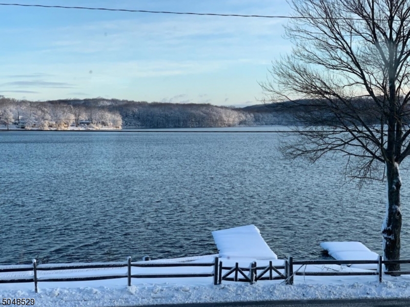 This special home is perfect for those seeking the serenity of beautiful lake views and being near a walkable small town with parks and train service to the city. You'll love the flow of the two finished levels. The upper level has a spacious living room open to a formal dining room, an updated kitchen with an island, and a ready-to-be-finished sunroom with vaulted ceilings. The master suite has lake views and a full attached bath. The lower level has a family room with fireplace, home study area, bedroom, office/guest room, a full bath, and laundry room. The workshop also has a mudroom area for entry from the over-sized garage. With dock access across the street, you can enjoy small boating and fishing on Lake Musconetcong. Rear deck 2020, central air 2018, roof 2014.