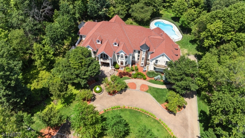This exceptional custom luxury estate blends timeless architecture with resort-style living on a cul-de-sac. This stunning home offers six spacious bedrooms, each with its own ensuite bath, creating the perfect layout for long-term guests. A grand circular paver driveway leads to the impressive facade & double-door entry, opening to a breathtaking two-story foyer with a sweeping butterfly staircase, ornate wrought-iron railings, & a crystal chandelier from Italy. The elegant interior features radiant heated floors throughout the chef's kitchen, formal dining room, & multiple gathering spaces ideal for entertaining. The great room showcases soaring ceilings, mezzanine balconies, oversized windows, & custom moldings, filling the home with natural light while highlighting the beautifully landscaped property. Custom hardwood floors with intricate inlay designs add warmth & sophistication throughout. A custom spiritual room provides a peaceful sanctuary for reflection or meditation. The full walkout basement expands the living space with a second kitchen, additional ensuite bedroom, & large entertaining area with dance floor. Luxury amenities include a private movie theater & ELEVATOR with a window which makes this a one-of-a-kind home. Outdoors, enjoy multiple terraces, a circular stone balcony, screened-in porch, & heated swimming pool, creating a true backyard resort. Located near local hospitals & transportation this estate offers both tranquility & convenience.