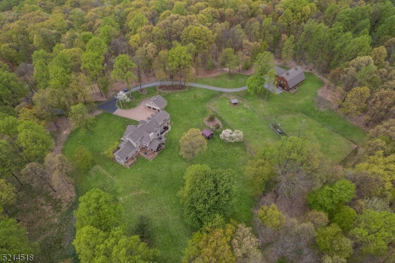 Cliffwood Farms is the quintessential lifestyle farm featuring 65 private wooded acres; the perfect place to relax and recharge. The main residence and barn are designed in a Post-and-Beam style that complements the natural surroundings. The property offers a wide variety of activities including hiking, horseback riding, gardening, and raising livestock. The home, built in 2014, captures the feeling of a relaxing getaway. The two-story Great Room with an impressive floor-to-ceiling stone fireplace is the centerpiece of the home. It's open to both the Kitchen and Dining areas, as well as a Wet Bar, making it a perfect place for entertaining guests or simply relaxing fireside. The 1st floor also includes the Primary Bedroom with a luxurious en-suite bath, a dedicated Home Office, and  Laundry Room.  Upstairs there are three additional Bedrooms, two Full Baths, Loft and Study. The unique Gambrel Style Post and Beam Barn satisfy both work and leisure needs with a 5 stall barn, radiant heated observation room including wet bar, half bath, and additional loft space. The sprawling yard and wooded acreage with trails and nature views make Cliffwood Farms a truly special property.  It is the perfect escape from the demands of daily life. Enjoy the tranquillity of country living while just minutes away from Mendham and Chester Boros.