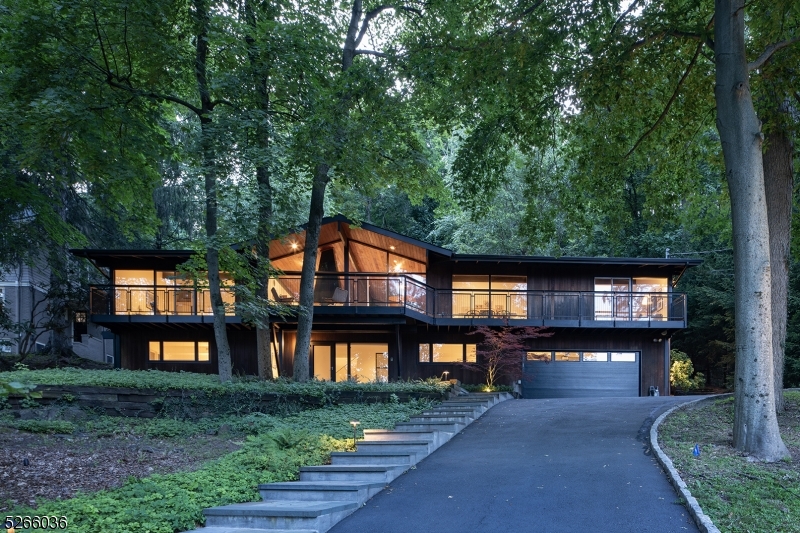 Exquisite, light filled Mid-Century Modern home located on one of the most coveted streets in Maplewood. This meticulously renovated 4 bedroom 2 full bath home provides luxury living at its best. With expansive floor-to-ceiling windows and beautifully set on a wooded lot backing to the South Mountain Reservation, this home offers all-season breathtaking views of the woods and the NYC skyline. As sunlight pours through the large floor-to-ceiling windows you are taken away to this tranquil and private oasis. The main level features wood floors, cathedral ceilings, a free standing wood burning fireplace in the striking living room. Spacious dining room, family room, renovated kitchen plus an oversized primary suite featuring cathedral ceiling, custom closets, fabulous bathroom plus  a stunning main level balcony with custom railing across front of home offers incredible entertaining and daily living. The lower level features a large foyer, two guest closets, three bedrooms and a renovated full bath. Heated 2 car garage with Tesla charging station. The patio and heated pool area are nestled in the Reservation offering unparalleled privacy and solitude.  Fireplace, chimney & flues in "as is" condition with no known issues.