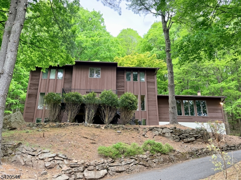 Don't miss this exceptional home located on one of Bridgewater's loveliest streets. This spacious home includes a private guest/in-law/au pair  suite, perfect for long stays. The architectural design combines late mid-century style with tasteful renovations, in a gorgeous natural setting. A unique open porch at the front entry provides relaxing outdoor space overlooking wooded sunsets. Featuring a center island with seating, stainless steel appliances, glass backsplash, maple cabinets and granite, the renovated kitchen is a delightful space filled with natural light with french doors leading to a serene deck and stone garden. Large rooms provide ample space for entertaining. The family room is anchored by a dramatic volcanic rock fireplace, soaring vaulted ceiling, and tall windows with abundant natural views. Primary suite is a spacious retreat with a spa-like renovated bathroom enhanced by radiant-heated floor double vanity, and luxurious walk-in shower floored with river stone. The basement is finished as a guest/in-law suite, with a recreation room, full bathroom, dining nook, and large bedroom. The expansive back deck is perfect for outdoor entertaining and enjoyment: an oasis surrounded by mature woods and historical stone walls. Don't miss this exceptional home located on one of Bridgewater's loveliest streets.