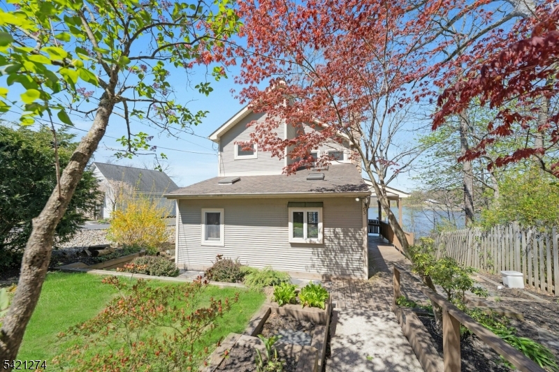 Escape to this charming lakefront chalet offering 2 bedrooms and 2 full baths, perfectly designed to create enduring memories, capture breathtaking water views and unforgettable sunsets. The main living area features a warm and inviting dining and living room that opens to a lakefront deck, ideal for relaxing, entertaining or dining al fresco. The beautifully updated kitchen, with a unique stained glass detail over the breakfast bar, is a standout, complete with granite countertops, stainless steel appliances, recessed lighting, and a skylight that fills the space with natural light. Upstairs, the primary bedroom is a true retreat with its own skylight, walk-in closet, and private lakefront balcony perfect for quiet mornings overlooking the water. Solid wood doors throughout are quality & add character.The full walkout basement houses the laundry room and provides additional flexible space with direct access to the outdoors. Outside enjoy the wraparound deck on the main level, or head down to the newer dock, which includes a canoe for immediate lake enjoyment. Additional highlights include a huge 2-car garage with an expansive loft area ideal for storage, a studio, or workshop and a generator for added peace of mind.  The location is convenient to several major highways and is approximately 1 hour commute to Manhattan by car. Optional HOA dues; buyer to verify. This is lakefront living at its finest, blending charm, comfort, and lifestyle.