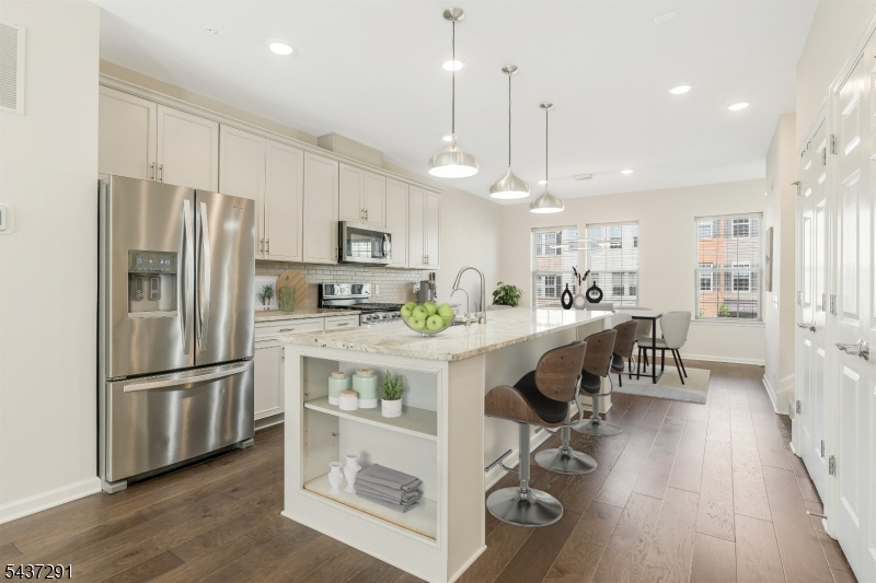 Best Value in Livingston & LOWEST Monthly HOA Fees. Stunning 4 Year Old Townhome, approx. 2000 sq ft of Modern living in the sought-after Livingston Square community. Built in 2021, this home features a flexible floor plan with numerous upgrades, ideal for today's changing lifestyles. The main level showcases an open-concept living, dining, and kitchen area bathed in natural light via oversize windows, upgraded wood floors, a built-in office nook, and a private deck. The gourmet center island kitchen boasts quartz countertops, stainless steel appliances, and a large double pantry. Upstairs are three spacious bedrooms and two full baths, including a luxurious primary suite with two walk-in closets and a tray ceiling. The laundry is conveniently located on the bedroom level. The ground level includes a sunlit office/den (potential 4th bedroom) and access to a 2-car garage with epoxy floors and Tesla charger. Other features include ceiling fans in every room, water softener, reverse osmosis filter, and Container Store closet systems in the 2nd, 3rd bedrooms. The home overlooks a beautifully landscaped green space (largest in the community) with a gazebo. Conveniently located close to train and bus with service to NYC, and within walking distance to Livingston Mall and the express shuttle to S. Orange train station. Close to world-class shopping at Mall at Short Hills, dining, parks/recreation, and top schools. Great Opportunity for Investors or quick move-in!
