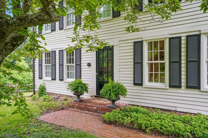 Experience country living in this exquisite, fully renovated vintage compound. Spanning five serene, level acres near historic Oldwick Village, this property offers timeless charm and modern sophistication. Both the main two-bedroom residence and the legal one-bedroom guest cottage (ADU) were completely updated in 2018 and 2025, featuring designer neutral finishes, gleaming wood floors, and custom millwork throughout. High-end architectural details abound, including a cedar shake roof, copper gutters, and true divided-light windows.Recent upgrades include new interior paint in the main house and cottage interior, california closets, millwork, custom bookcases, custom lighting, hot tub, patio/rear landscaping, water softener and fencing. The gourmet open-concept kitchen boasts custom ivory cabinetry with inset doors, a farm sink, and an expansive quartzite island breakfast bar with a double ogee edge. Modern conveniences include an induction cooktop and a panel-integrated refrigerator that blends seamlessly with the cabinetry. A sun drenched breakfast area is nearby.  Adjacent to the kitchen is a dedicated laundry zone. The primary suite is a private sanctuary featuring California closet, a luxurious bath with marble tile and a multi-fixture rain shower. The grounds are equally impressive, offering professional landscaping with ambient lighting, private patios for both homes, and a main terrace equipped with a premium hot tub on a custom cedar platform.