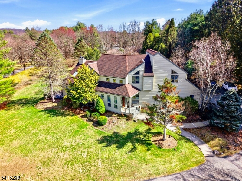 Set behind a long, private approach and surrounded by mature trees, this 4-bedroom, 4-bath residence offers a rare sense of seclusion, space, and light in one of Boonton Township's most desirable settings. From the moment you enter, the home opens into a dramatic, light-filled living space defined by soaring ceilings, skylights, and walls of glass. At its center, a striking fireplace anchors the room, creating an atmosphere that is both expansive and inviting, equally suited for quiet evenings or entertaining on a larger scale. The layout has been thoughtfully designed to support the way people live today, offering multiple living areas, a finished lower level, and flexible spaces for work, relaxation, and hosting. With four full bathrooms, the home provides both comfort and convenience for residents and guests alike. Outdoors, the property transforms into a private retreat. Expansive lawns, a solar-heated pool, a Full House back-up generator, and natural surroundings create a setting that feels far removed from the everyday, while still offering easy access to major routes and nearby amenities. Extensively maintained and improved, the home reflects a level of care and investment that is increasingly rare to find. This is more than a home, it is a lifestyle defined by privacy, light, and the freedom to live without compromise.
