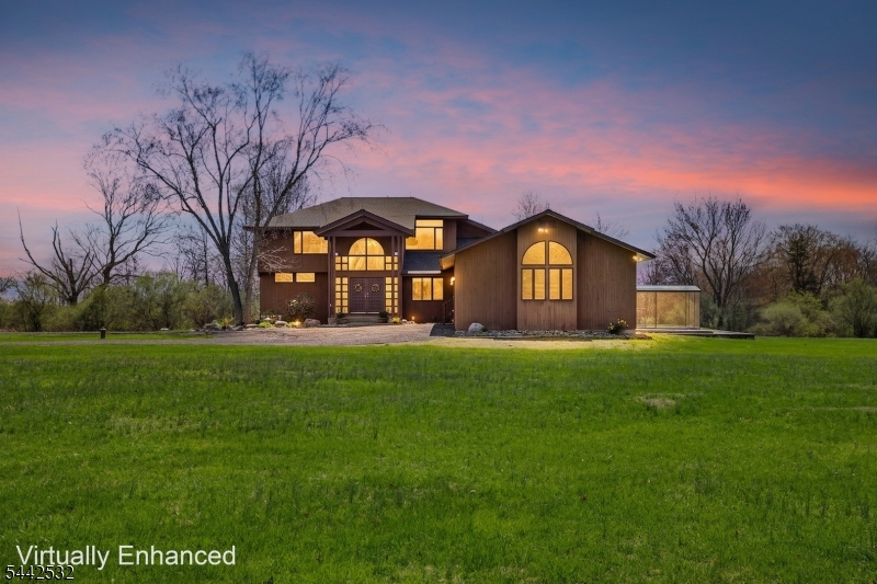 Set on over 11 acres of open, picturesque land, this beautifully updated contemporary home offers exceptional privacy and modern comfort on the border of Hopewell and East Amwell with a Hopewell address. Positioned at the end of a recently paved 0.25-mile driveway, the setting is serene and impressive. Inside, soaring ceilings, expansive windows, and new skylights fill the home with natural light, framing tranquil views in every direction. The open layout connects the living areas to a spacious deck, ideal for entertaining. The flexible floor plan features a main-level primary suite, an additional first-floor bedroom or office, and two upstairs bedrooms overlooking the central living space. All three full bathrooms have been thoughtfully renovated with high-end finishes, complemented by fresh paint throughout. Recent upgrades, including a new roof, added skylights, updated systems, and a sump pump, reflect a significant investment in the home's quality and longevity. A full basement, three-car garage, and a propane-powered generator provide additional functionality, while a new washer, dryer, and utility sink enhance everyday living. The expansive acreage offers endless possibilities, while the location combines the prestige of a Hopewell address with the advantage of East Amwell's more favorable local tax structure. A rare opportunity to own a thoughtfully updated home on substantial acreage.