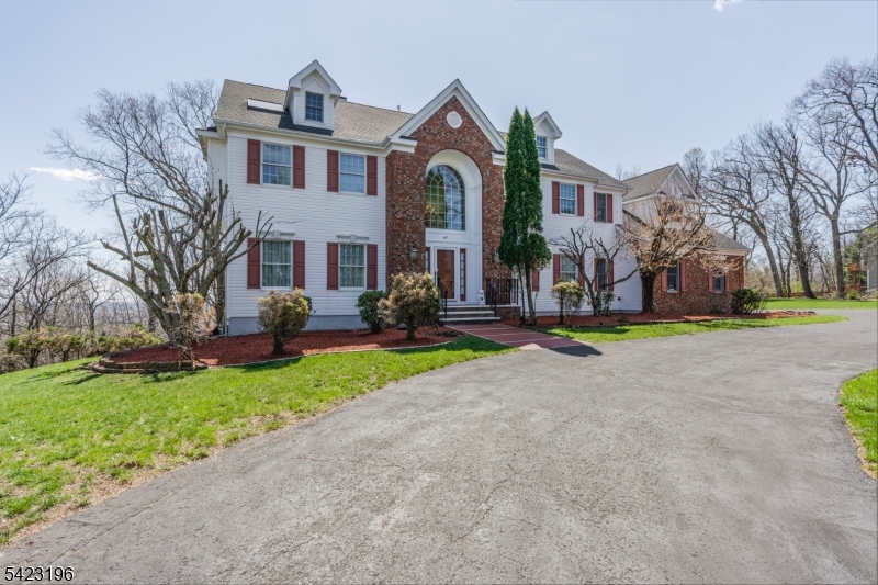 Set on a private hilltop in Green Brook with panoramic valley and sunset views, 47 Scheurman Terrace is a distinctive custom colonial offering three levels of beautifully finished living space on a wooded, ridge-top lot. A long private drive winds up through mature landscaping to a striking brick and clapboard facade. Inside, a dramatic two-story foyer opens to gracious formal living and dining rooms, each filled with natural light. The sun-drenched great room features a two sided gas-burning fireplace and oversized windows framing the view, and flows seamlessly into a gourmet center-island kitchen with abundant cabinetry, generous prep space, and a bright breakfast nook. Sliding doors lead to an expansive 39-foot entertaining deck overlooking the valley below. A private home office with its own balcony, powder room, laundry, and oversized two-car garage complete the main level. Upstairs, an expansive primary suite is a true retreat with a private balcony, dual walk-in closets, and a spa bath with soaking tub and separate shower. Three additional generously sized bedrooms are served by two additional full baths. The walk-out lower level lives like a complete second residence, featuring a full second kitchen, dining area, oversized great room, full bath, and a generous flex room with private entry and direct access to the lower deck. Mature landscaping, a long private drive, and true ridge-top seclusion. Minutes to I-78, Route 22, and NJ Transit.
