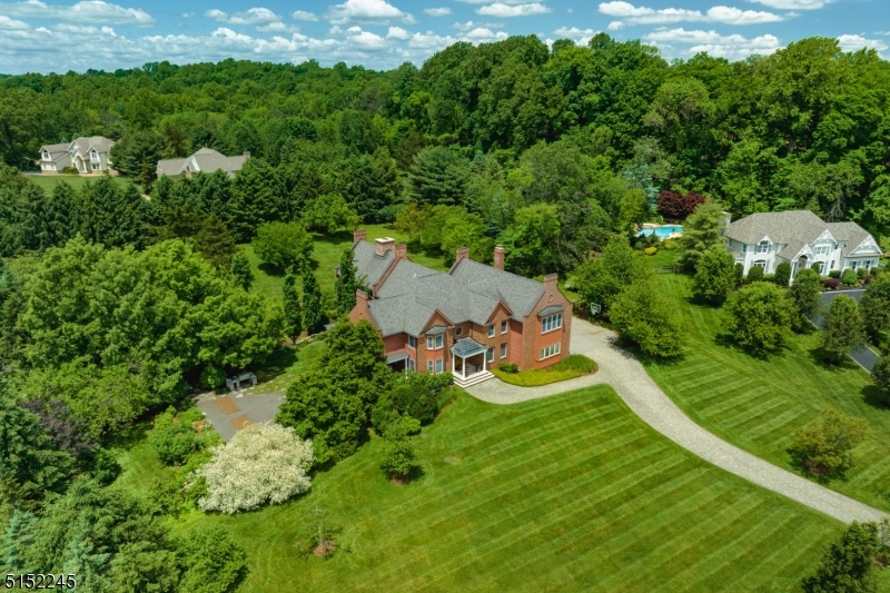 Designed by renowned architect Dennis Wedlick, this custom home offers a meticulously planned layout using the highest quality materials. The public rooms on the main level are perfect for any gathering, intimate or grand.  French doors from both the Dining Room and Great Room lead to a wraparound covered porch, providing seamless overflow when entertaining. Walnut floors grace the first and second levels, providing a rich, warm appearance. The kitchen, outfitted with high end appliances including Sub-Zero and Viking, boasts alder wood cabinetry and two center islands. From the kitchen, your gaze is drawn to the dramatic two-story timber frame constructed Great Room with Rumford double sided fireplace and chimney created using imported stone. A sweeping, iron and wood spiral staircase leads to both an upper level loft and to the finished basement. Three walls of windows, each with alder wood framing, bring the outdoors in, creating a stunning view of the grounds during any season. Upstairs, the Primary Suite offers a full bath plus a spacious dressing room with French doors leading to a balcony overlooking the side yard. Four additional bedrooms (two of which have spiral staircases to private lofts), two full baths, and a loft overlooking the striking Great Room complete the level. The finished walk-out lower level delivers a media room with two-sided gas fireplace, kitchenette, exercise room, Finlandia electric sauna,  bedroom, plus two full bathrooms.