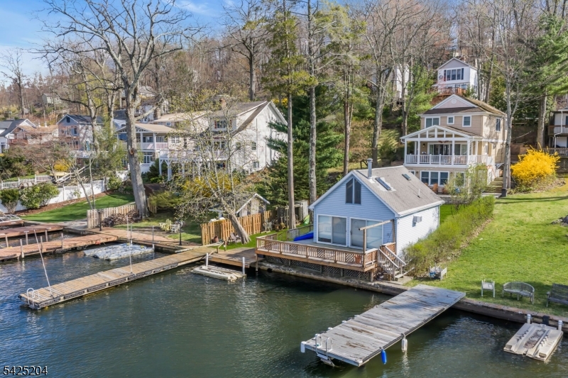 Two Homes, One Exceptional Lakefront Lifestyle! A rare and exciting opportunity to own a private compound or generate income while living your lakefront dream. The main home, built in 2008, showcases an open-concept design with a gourmet kitchen flowing seamlessly into the dining and living areas, centered around a cozy gas fireplace and opening to a covered deck with breathtaking lake views perfect for relaxing or entertaining. A first-floor bedroom, full bath, and laundry add convenience, while the second level offers a spacious primary suite with walk-in closet and private bath, plus three additional bedrooms and a full guest bath. The finished walk-out lower level features a sunlit family/game room with gas wood stove, and sliders to a lakeside patio. The charming second home offers easy one-level living with a warm, inviting great room, wood stove, and open kitchen/dining space. A bedroom with en-suite bath and a loft for guests or a home office capture stunning lake views. Step out to your private deck, just moments from the dock ideal for dining, entertaining, and enjoying one of the lake's best fishing spots. Set beneath a majestic chestnut tree and located within walking distance to town, restaurants, shops, parks, and tennis courts. Enjoy year-round activities from boating, paddleboarding to ice skating and snowmobiling this is lake living at its finest! Walk to town location with restaurants and shops. Local park and tennis courts. Swim, boat, fish and more!