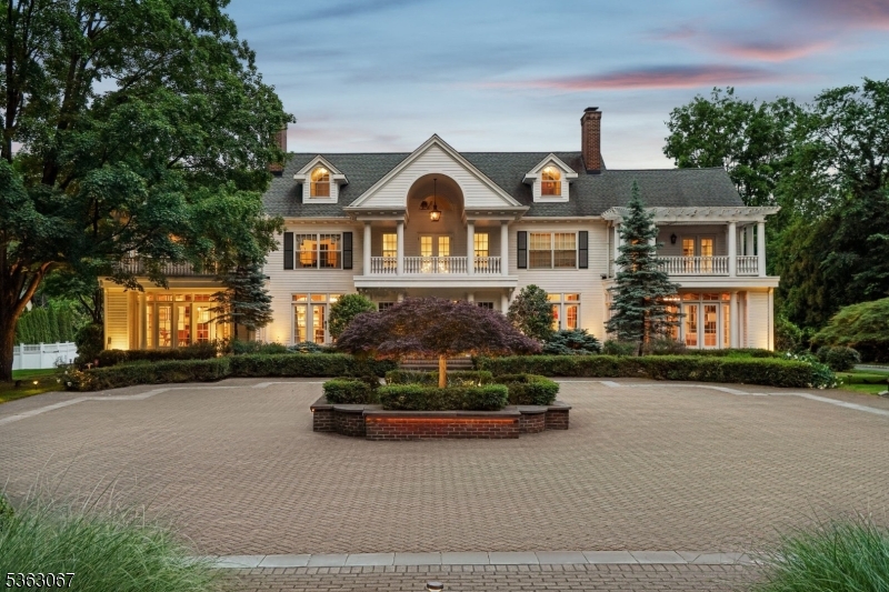 Tucked behind the gates of prestigious Llewellyn Park, this distinguished estate blends timeless elegance with modern luxury on nearly 2 acres. Rebuilt from the foundation in the 1990s and beautifully renovated in 2022, the 6-bedroom, 8.3-bath residence spans five levels with elevator access. A grand staircase and soaring ceilings lead to herringbone wood floors, arched doorways, and sun-drenched living spaces. The formal living room with a marble fireplace opens to a sun-drenched sitting room, while a character-rich office with a spiral staircase offers direct access to the primary suite above. The banquet-sized dining room, adorned with a Carrara marble fireplace and Murano-style chandelier, flows into the chef's kitchen featuring radiant heated floors, top-tier appliances, and a bright breakfast area. Upstairs, the expansive primary suite is a private haven with dual spa baths, two walk-in closets, a dressing room, gym, coffee bar, and a serene balcony. A separate level holds a recreation room with en-suite bath, sitting area, and storage. The finished basement includes a custom, soundproofed recording studio ideal for music, podcasting, or content creation. Outside, enjoy a heated infinity pool, spa, pergola with retractable awning and fireplace, sport court, and a separate 1-bed/1-bath Carriage House perfect for guests. Sq footage is approx*