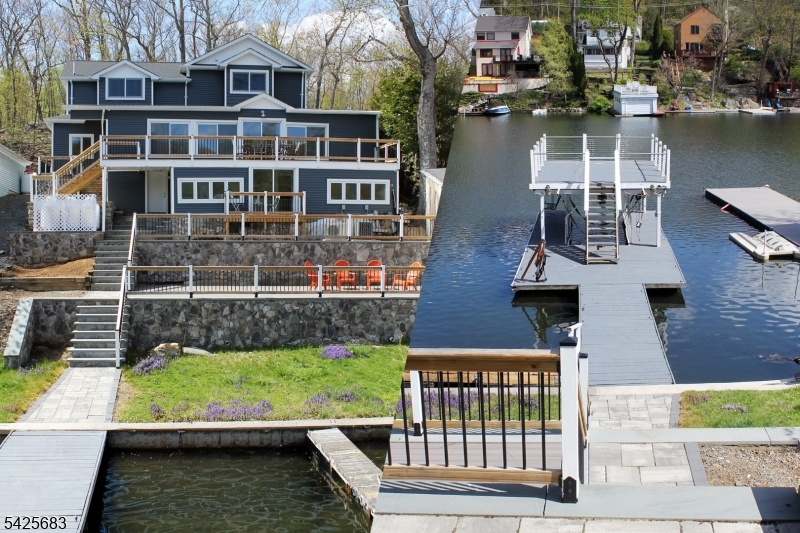 Updated lake front with designer kitchen, three bedrooms, four bathrooms, 2 car garage and more! This lake front has been remodeled and it shows beautifully. Some of the updates include a designer kitchen with butler's pantry, four new bathrooms, new roof, new heating and cooling, new siding and three new decks with composite surfaces and custom railings. These decks provide almost 1,000 square feet of outdoor living space that overlooks the peaceful cove setting and at the water there is a covered boat port with a private sun deck. The bedrooms and living room have new wood floors and the kitchen and dining room feature new tile flooring. The first floor master suite features ceilings almost ten feet high, beautiful views of the water and two walk - in closets. You'll love the new bathroom with a soaking tub, rainfall shower, double sinks and views of the water. In addition there is a finished walk-in attic that measures 21 x 16 that is heated and air conditioned. And if you ever want to work from home there is a private area on the lower level that makes a perfect home office workspace with a full bath and more views of the water. If you're looking for a move-in condition home with a peaceful setting you'll want to see this one.
