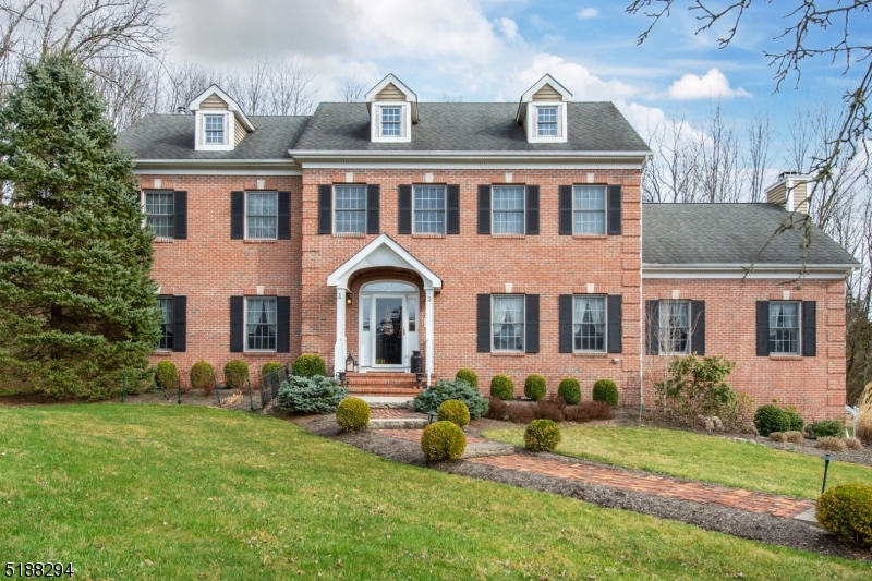 Great brick front colonial in a fantastic cul de sac location - 3 minutes to the Gladstone NJT train!  Set in the tiny hamlet of Gladstone, this home offers freshly refinished hardwood flooring throughout the first floor, 9' ceilings for a sense of space and an incredible great room with cherry flooring, cathedral ceiling, wood burning fireplace and French doors to deck overlooking private yard.  Country eat-in kitchen with granite counters and center island, formal living and dining rooms and 1st floor bedroom/office with adjacent full bath complete the living space.  Four spacious bedrooms with hardwood flooring on the 2nd floor and 2 full baths (including primary en suite) round out the perfect living situation!  Unfinished basement with 9-10' ceilings has limitless possibilities. Room dimensions per homeowner.