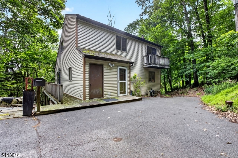 The Mountain Lake community is one of New Jersey's best-kept secrets, and this is your chance to get in on it. This custom lake house boasts space inside and out, stunning views, and the privacy of a vast wooded lot - all on a serene hilltop setting. On the main level, an open-concept kitchen looks out onto an expansive living room/dining area. Cathedral ceilings add to the spacious feel, and twin skylights let in copious amounts of sunlight or starlight depending on the hour. A wraparound deck is easily accessed from inside through three sliding glass doors. The primary bedroom is nestled just off the living room, and a Jack and Jill bathroom allows entrance from both the bedroom and the kitchen. Upstairs you'll find the other pair of bedrooms, each with its own unique attribute: the bedroom nearest the stairs features a walk-out balcony, while the far bedroom adjoins a full Jack and Jill bathroom with hallway access. The basement features a living room-style den with kitchenette, as well as a third full bathroom, and is surrounded by a second walkout deck. To get to the boathouse and dock, take the winding main driveway down to street level, or use the side-access shared driveway if you prefer a straight shot. The home's position offers the perfect vantage point of Mountain Lake and the hilly green expanses of North Jersey for miles. The community features on-the-water dining, the exclusive Liberty Township Beach, and access to the southern trails of Jenny Jump State Park.