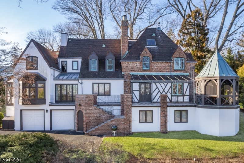Nestled on Summit's North End, a head turning 4 Bedroom, 4.2 Bathroom, "Tudor-Style", one-of-a-kind house with incredible curb appeal on a serene street with no through-traffic. Ancient Highland manor house with cutting-edge modern design sits on 1.75 acres of private grounds with spectacular views of the NYC Skyline. New state-of-the-art custom Chef's Kitchen featuring Gaggenau appliances, Cesar cabinetry, waterfall Caesarstone ceramic countertop, and open Breakfast Area leading out to expansive Stone Terrace. Living Room with stately French fireplace and original mantle. Sunken Entry Foyer that "wows  with elegant Powder Room. Refreshed En-Suite Family Room with custom built-ins, large bay window with window seat, Full Bathroom and separate side-door entry. Second Level Primary Suite is its own wing with ample closets, hardwood floors, sunlight and a gorgeous Bathroom with large soaking tub. Refinished sunlit En-Suite 4th Bedroom on 3rd floor with charming sunken sitting area and Full Bath. Lower Level features a "Pub Style" Recreation Room, a custom Wine Cellar, a newly finished Laundry Room, and a large Gym. Featuring authentic custom heavy oak doors, original oak flooring, stained-glass windows, arched doorways, unique vaulted ceilings, and detailed plaster moldings throughout the entire home. Incredibly special opportunity for the discerning homeowner seeking the best schools, nearby NYC transportation, amazing eateries, shopping and more. 65 Edgewood will not last!
