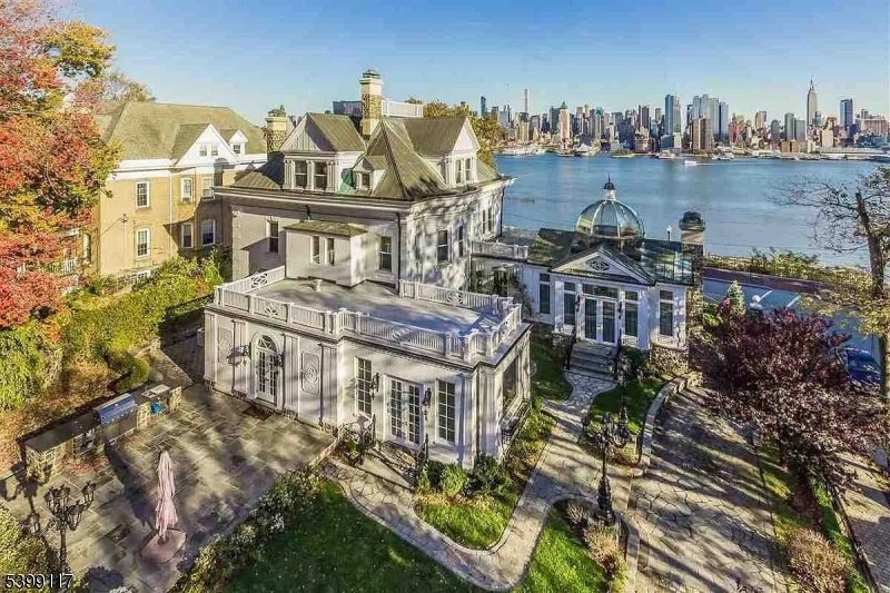 Commanding one of the most extraordinary viewpoints on the Hudson, 1 Hamilton Ave delivers a level of presence rarely found in the New York metro market. Perched high above the river, it captures a sweeping, cinematic panorama of Manhattan that instantly defines the home as a true statement property.Beyond the grand columned entrance, the interior showcases refined craftsmanship: custom woodwork, detailed moldings, stained glass accents, marble floors, ornate fireplaces, and hand-finished ceiling artwork that gives each room a distinct character.The Conservatory serves as a dramatic centerpiece, crowned with a soaring glass dome, warm onyx flooring, and wraparound windows that bring the skyline directly into the space. The formal dining room features a beautifully crafted ceiling and herringbone flooring, creating the perfect setting for elevated hosting.The chef's kitchen comes equipped with professional-grade appliances and bespoke finishes throughout. A second-floor terrace framed by elegant arches offers unmatched river and city views ideal for quiet mornings or evening gatherings.Each bedroom carries unique decorative details and refined wall finishes. The top level adds versatility with a private two-bedroom, 1.5-bath suite complete with its own entrance and upscale kitchen.Manicured grounds, Paris-style lighting, a bluestone patio, and a charming gazebo complete this rare residence a timeless estate for the buyer seeking something truly irreplaceable.
