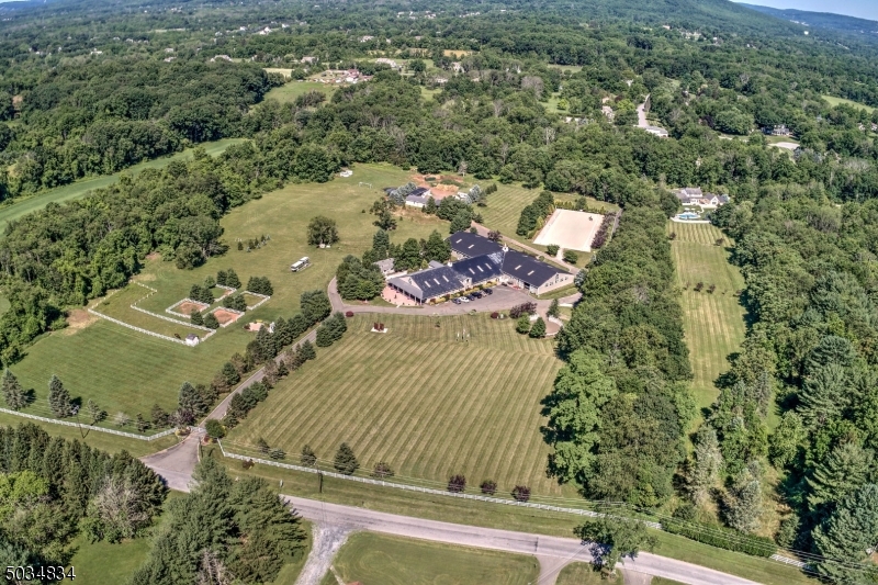 World-class Equestrian facility created & designed by international competitor and trainer where the utmost needs of horse and rider are met. Nestled on 27 lush acres. Near all things equestrian. European designed custom stable, features two rubber paver aisles, 24 spacious box stalls, grooming and wash stalls, climate controlled offices, tack rooms, laundry and baths.  High ceilings and windows in every stall for great ventilation.  Solarium and round pen.  Free span approx. 200'x80'indoor riding hall with viewing area and all purpose footing, outdoor arena has recent new footing with sprinkler system.  Courtyard features another 8+ box stalls, hay and bedding buildings.  The workshop complex features garages and more visitor stalls. Attention to detail abounds with beautiful wood finishes.  Custom home