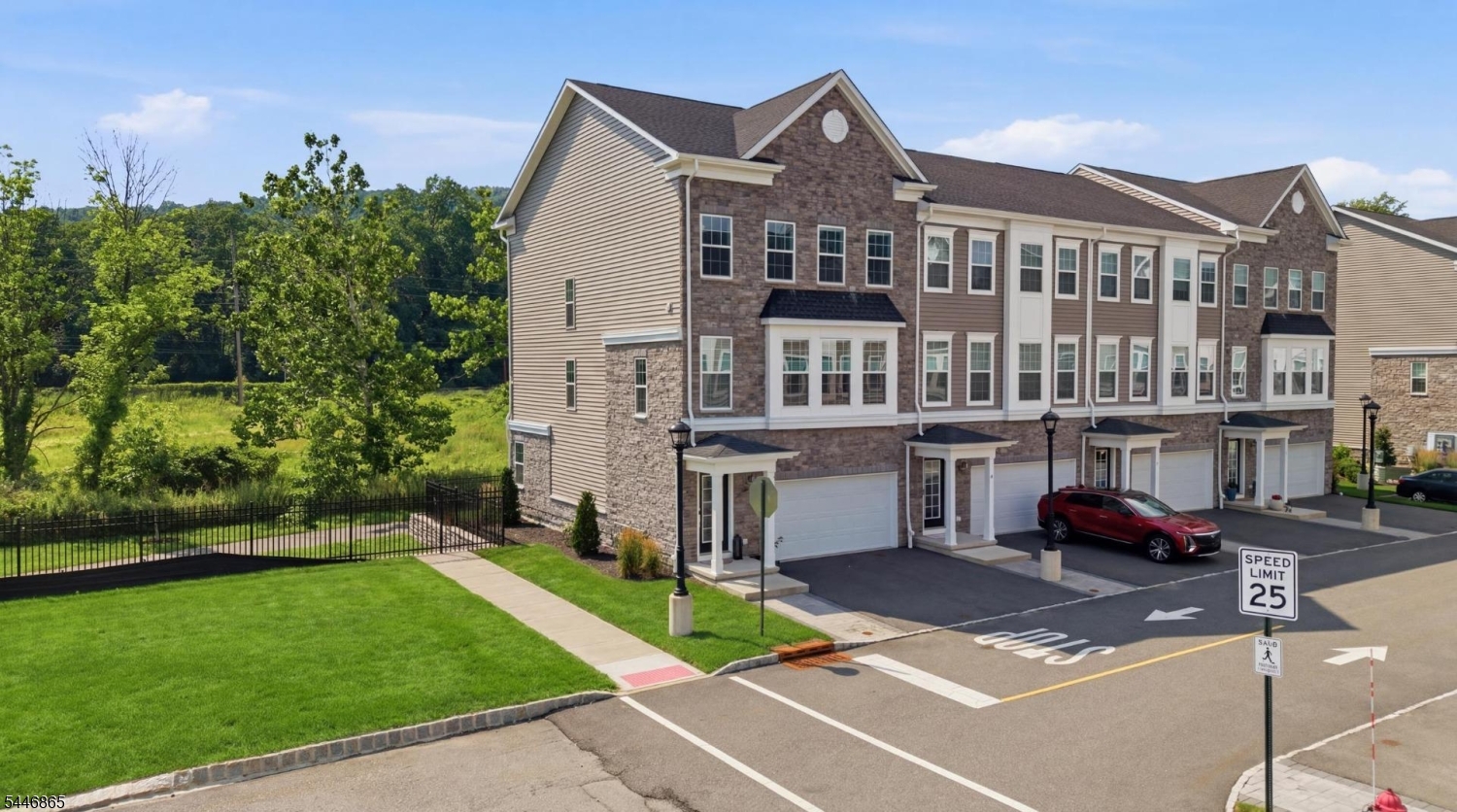 Welcome to this beautifully maintained 2022-built corner townhome offering 3 bedrooms, 3.5 baths, and a spacious 2-car garage. Filled with natural light from its premium corner location, this home features an open-concept main level with hardwood floors, a stunning kitchen with quartz countertops, stainless steel appliances, a large center island, pantry, and seamless flow into the dining and living areas. Step outside to your private deck directly off the kitchen, perfect for entertaining or enjoying peaceful views of the surrounding green space. Upstairs, the spacious primary suite offers a walk-in closet and en-suite bath with dual vanities and a large tiled shower, while two additional bedrooms, a full bath, and second-floor laundry complete the level. The ground floor offers a versatile recreation room with a full bath, walkout patio, and private backyard space ideal for guests, a home office, or relaxing outdoors. Conveniently located just minutes from the Morris Plains and Morristown train stations, major highways, shopping, restaurants, parks, and downtown Morristown, this home combines modern comfort, low-maintenance living, and an unbeatable location.