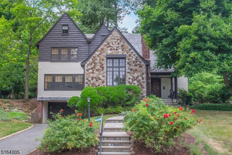 Situated on one of the prittiest tree-lined streets in town, this Tudor style home will charm you the instant you enter the living room with its Cathedral beamed ceiling, stone wood burning fireplace and majestic windows. From here you enter the bright modern family room with its sleek wall unit and numerous windows. It is the perfect place to relax,  read a book, or have a card game. Entertain in the dining room which has a built-in wall of bookshelves which give it a modern library feel.. Ask about the custom-built expandable table which will be for sale. If you are looking to renovate a ktchen to your specifications, this is the perfect house. Exit from the kitchen or dining room to the screened in porch where you can relax with your morning coffee or pre-dinner cocktail. A bedroom/office with ensuite bath, and powder room complete the first floor. On the second level you will find 4 ample size bedrooms. The Primary suite offers 2 wallk-in closets plus 2 built-in units for additinal storage. The primary bath has a stall shower. If you are looking for more storage, there is a walk-up attic with a vast amount of storage space. Head down to the lower level to a playroom, laundry room, half bath, and utiity room. This home has all the space you will ever need and affords easy access to downtown South Orange with stores, restaurants, theater, and train to NYC.