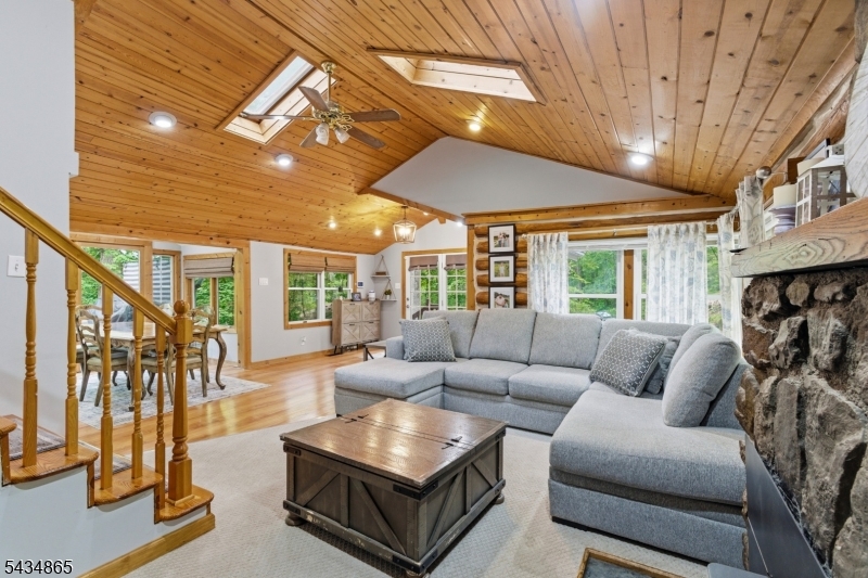 Custom Lake Mohawk log home with an architecturally pleasing addition blending rustic charm with modern amenities and lifestyle living. Expanded circa 2005, this inviting home offers an open-concept design, spacious rooms, and the warmth and character buyers seek in a Lake Mohawk retreat. The first floor features a welcoming foyer, vaulted pine ceilings, French doors, skylight, and a classic Crane fieldstone wood-burning fireplace. The updated kitchen offers abundant counter space, cabinetry, and storage, while the open dining area flows seamlessly for everyday living and entertaining. A first-floor bedroom and full bath with separate jetted tub and stall shower offer flexibility for guests, home office space or one floor living. Step outside onto the expansive entertaining deck overlooking a private setting with seasonal views of Lake Mohawk, perfect for relaxing or hosting gatherings. The substantial second-floor addition offers generously sized bedrooms and bathroom with vaulted ceilings and walk-in closets, creating comfortable private retreats. The walk-out basement adds bonus space with laundry, workout area, and ample storage. Additional highlights include a storage shed, solar panels-owned-which buyer may assume service if desired, central AC. Enjoy all Lake Mohawk Country amenities including power boating, beaches, social clubs, restaurants and pubs...Optional pool ,tennis/ pickleball, LMCC golf memberships available. 2021 2 bedroom septic. Recording devices in home.