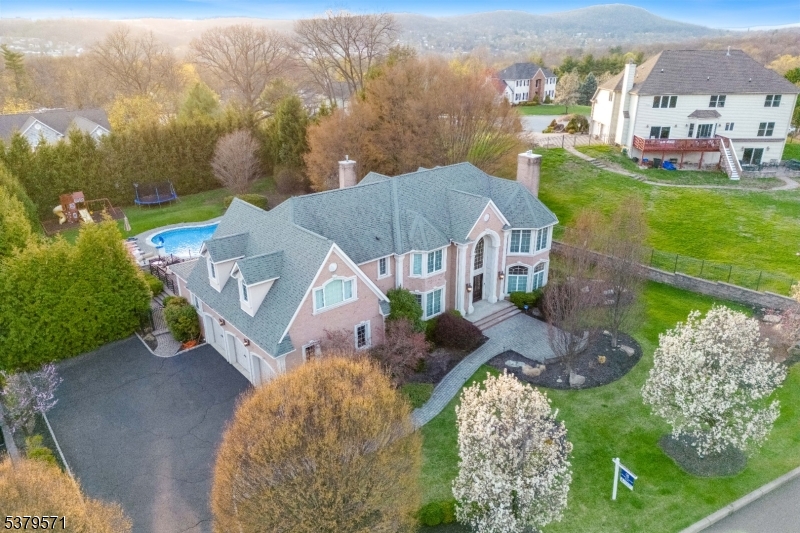 Situated on one of North Haledon's most desired cul-de-sacs is this incredible brick estate, featuring 7,500 feet of beautifully finished living space on a perfectly manicured 2/3 acre. Enter through the grand two-story foyer and enjoy elegant formal living and dining rooms, a dramatic great room with soaring ceilings and fireplace, massive eat-in chef's kitchen with additional living room, and main floor bedroom with full bathroom. Upstairs, a luxurious primary suite on its own wing, with 3 more bedrooms including another bedroom suite. The sprawling basement includes a recently added bar, a gym, home office, full bathroom and more. Outside, entertain in your resort-style backyard featuring a heated pool, spa, outdoor kitchen, koi pond, and playground, encased by lush landscaping and matured privacy trees. Additional highlights include custom millwork, oversized 3 car garage, water feature, and smart home upgrades. Located near parks, top rated schools, easy commute to NYC.