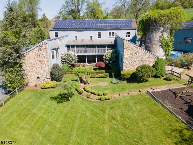 **Seller will consider owner financing with 25% down payment**. One of a kind Historic barn conversion graciously situated on 7.8 bucolic ac offering 5000+ SF of living space suitable for multigenerational living. The main part of the home is comprised of the cavernous former c1800s dairy barn restored down to the original post and beam structure with massive hand-hewn exposed beams, original 1800s barn floors, and original red stained pumpkin pine barn siding utilized to build the custom kitchen cabinets & trim throughout the house. Abundant windows and skylights allow plenty of light and multiple sliding doors open onto a covered porch overlooking the courtyard.  A brick fireplace with wood stove adds additional ambiance. 2 Open lofts offer multiple possible uses " gym, art gallery/studio, game room, and more. 1st flr primary suite with attached full bath with two vanities, jetted tub and stall shower.  In addition to the loft areas the 2nd flr offers 2BRs - 1 with en suite full bath, and 1 serviced by the full hall bath. Attached inlaw suite with separate entrance offers an eat-in kitchen and living area with wood stove. Mudroom/service porch connects to the c1740 carriage house now a 2c garage with 2-room loft with exposed beams, full bath, and private balcony. The attractive wood & stone exterior and the remains of the original silo add to the charm of the property and courtyard. Income generating outbuilding with 6 separate rentable garage bays with lockable doors.
