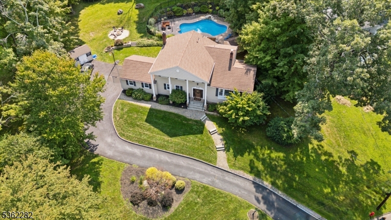 Set on a quiet, tree-lined street in Randolph's sought-after Shongum Lake area, this elegant Colonial sits on nearly 0.8 acres of landscaped property and includes lake rights, offering year-round recreation in a peaceful neighborhood setting. With 4 bedrooms, 2.5 baths, and an attached 2-car garage, this home blends timeless style with modern comfort. Step into a welcoming foyer that opens to a sun-filled living room with vaulted ceilings and an open view of the dining area below, perfect for everyday living. The updated kitchen features rich wood cabinetry, SS appliances, custom tile backsplash, and a center island perfect for casual meals and entertaining. An oversized family room with stone fireplace, custom built-ins, and French doors to the backyard is the heart of the home. A powder room and garage access complete this level. Upstairs, the primary suite offers two closets and a private bath with stall shower. 3 additional bedrooms share a full hall bath with tub, while a nearby laundry area adds convenience. A finished basement offers flexible space for a home office, gym, or playroom. Enjoy warm-weather living in the private backyard with a large patio, retractable awning, and an in-ground pool with waterfall. Shongum Lake access adds even more to love, with swimming, kayaking, fishing, and seasonal community events just moments away. Close to top rated schools, shopping, dining, and parks this move-in-ready home is the perfect combination of lifestyle and location.