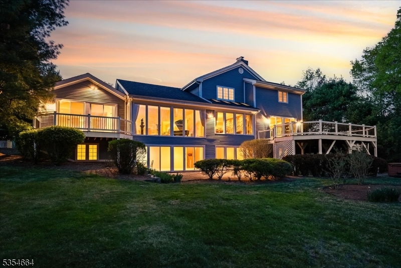 Situated directly across from the prestigious Mendham Golf & Tennis Club, this exceptional estate is a true haven for golf enthusiasts. Set on over five acres of exquisitely landscaped grounds, the property offers exceptional privacy and a tranquil, park-like atmosphere in the heart of Northeast Mendham. Designed by Anthony Paragano, the home features a refined modern aesthetic that blends seamlessly into its natural surroundings. Inside, sun-drenched interiors and expansive floor-to-ceiling windows create a warm, inviting ambiance throughout. The gourmet kitchen opens to a spacious deck ideal for al fresco dining, with views of a thriving butterfly garden, perfect for entertaining or unwinding in nature. The first-floor primary suite offers a peaceful retreat with its own private access to the outdoors. The walk-out lower level is an entertainer's dream, boasting another wall of floor-to-ceiling windows, a guest suite with full bath, and flexible recreation space. Conveniently located near Morristown with its NYC direct train, and access to myriad top-rated schools, this home offers the best of luxury, location, and lifestyle.
