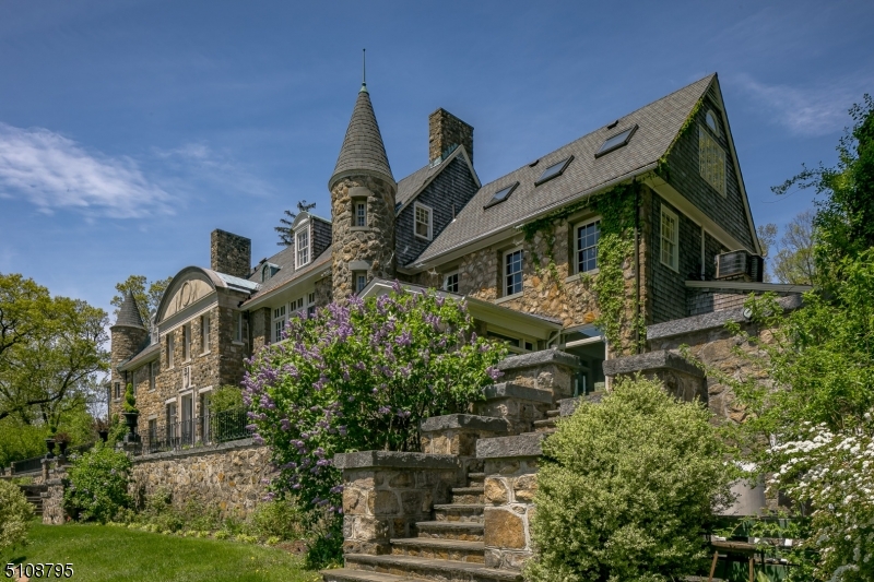 The magnificent Somerset Hills panoramas and incredible sunrise views from this stunning elevated vantage point are rare. Architecture rendered in stone, complete with turrets and towers, lends a sense of whimsy to the Craigmore estate. Over 12,000 square-feet of living space is arranged on three formal floors, befitting the baronial lifestyle of former owner Charles Engelhard Sr. The floor plan flows easily from one breathtaking space to the next.  Highlights of the layout include 7 fireplaces, flooring of oak in select rooms, high ceilings, and multiple sets of french doors opening to view-filled bluestone and grass terraces. There is a sunken conservatory overlooking stunning countryside vistas, a welcoming center island kitchen connecting to the breakfast and family rooms, and a partially finished basement with a temperature-controlled wine cellar and two insulated storage rooms. On the second floor's flexible layout, six bedrooms include a primary suite wing. Originally utilized for staff members, the third floor is currently arranged as two wings. One wing provides an oversized office and bedroom with full bath; the other a den, office, studio and two full baths plus an expansive recreation or exercise space.  An elevator services the 1st & 2nd firs. Stone terraces and patios step down to a heated pool with fountains, a koi pond and gardens, all providing a perfect venue for warm weather entertaining. In the front there is a stone wall enclosed courtyard with fountain.